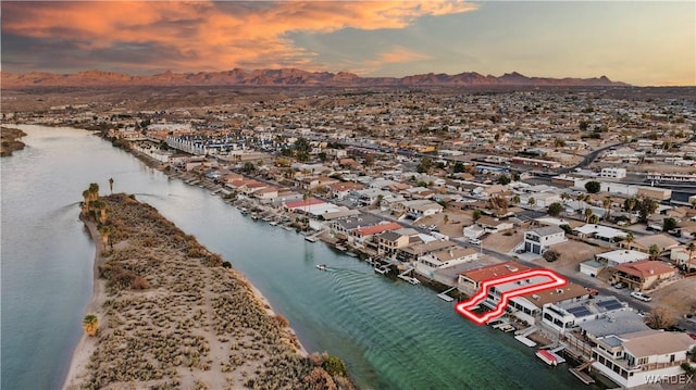 aerial view at dusk with a residential view, a water view, and a beach view