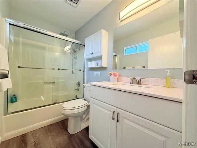 full bathroom featuring shower / bath combination with glass door, visible vents, toilet, vanity, and wood finished floors