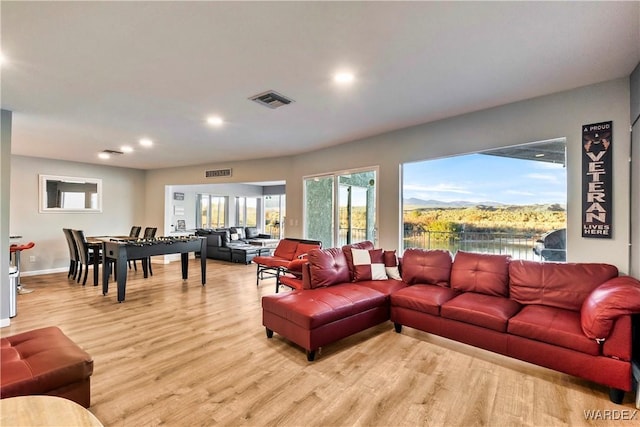 living area featuring baseboards, visible vents, a water view, light wood-style floors, and recessed lighting