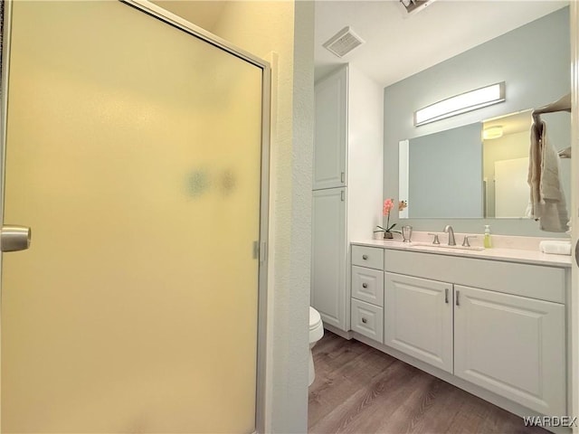 full bath with visible vents, toilet, wood finished floors, vanity, and a shower stall