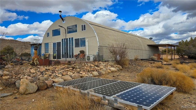 rear view of property with a gambrel roof and ground mounted solar panels