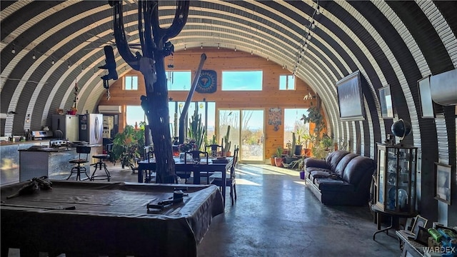 interior space featuring concrete flooring, pool table, and vaulted ceiling