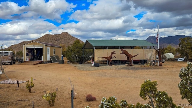 rear view of property with a mountain view and an outdoor structure