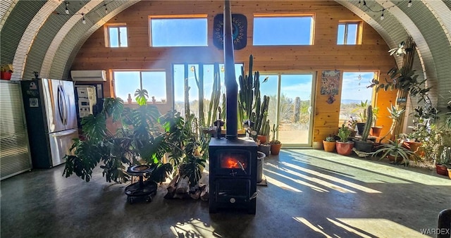 interior space with a wood stove, wood walls, a wall mounted AC, and freestanding refrigerator