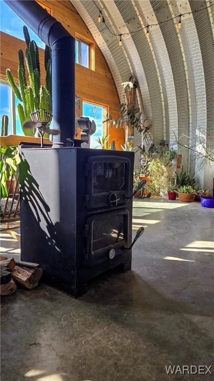 details with a wood stove, wood walls, and unfinished concrete flooring