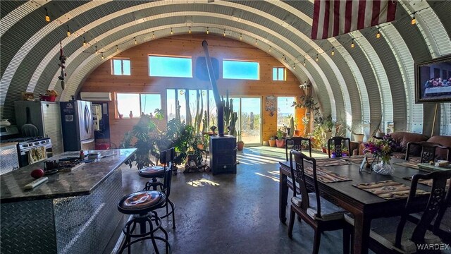 dining space featuring arched walkways and high vaulted ceiling