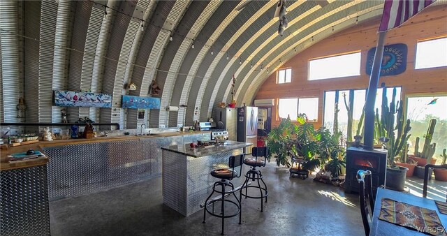 bar with a sink, high vaulted ceiling, concrete flooring, and freestanding refrigerator