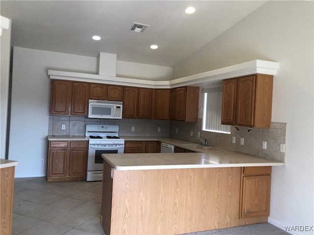 kitchen with visible vents, light countertops, white appliances, a peninsula, and vaulted ceiling