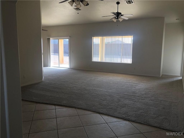 empty room with ceiling fan, a textured ceiling, visible vents, carpet floors, and tile patterned floors