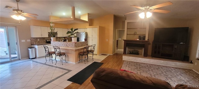 living area featuring visible vents, baseboards, light tile patterned flooring, and a ceiling fan