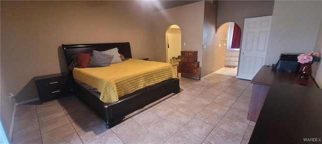 bedroom with arched walkways and light tile patterned flooring