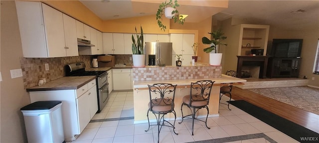 kitchen featuring under cabinet range hood, decorative backsplash, stainless steel appliances, light tile patterned flooring, and white cabinetry