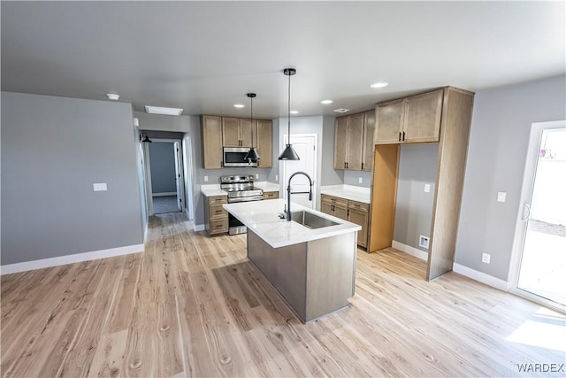 kitchen featuring stainless steel appliances, light wood-type flooring, a sink, and baseboards