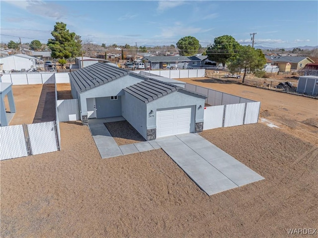 view of front of property featuring metal roof, stone siding, a fenced backyard, and stucco siding