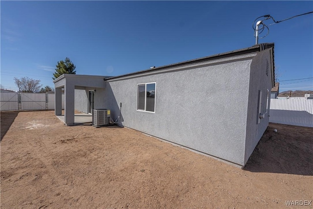 back of property featuring stucco siding, fence, and central air condition unit