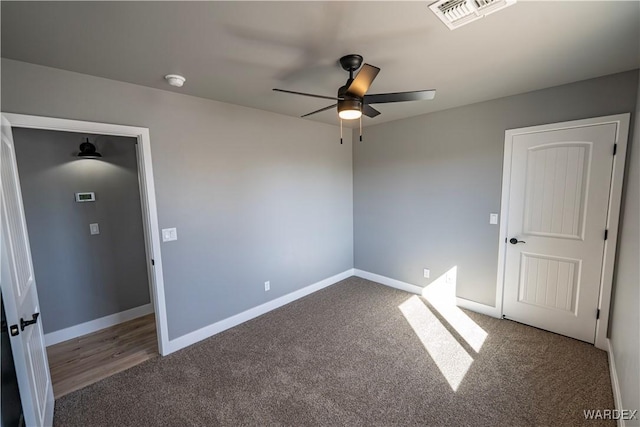 carpeted empty room with baseboards, visible vents, and ceiling fan