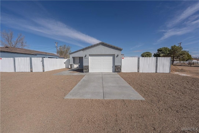 exterior space with a garage, fence, concrete driveway, and an outbuilding