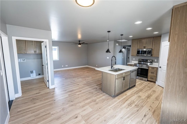 kitchen with baseboards, light wood-style flooring, appliances with stainless steel finishes, light countertops, and a sink