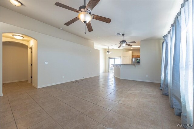 unfurnished living room featuring arched walkways, light tile patterned flooring, visible vents, and baseboards