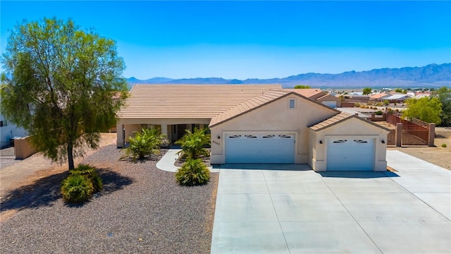 6053 S Klamath Loop, Fort Mohave, AZ 86426 - view of front of property with a mountain view, an attached garage, driveway, stucco siding, and a tile roof