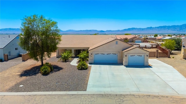 6053 S Klamath Loop, Fort Mohave, AZ 86426 - view of front of property featuring a garage, a mountain view, concrete driveway, stucco siding, and a tiled roof