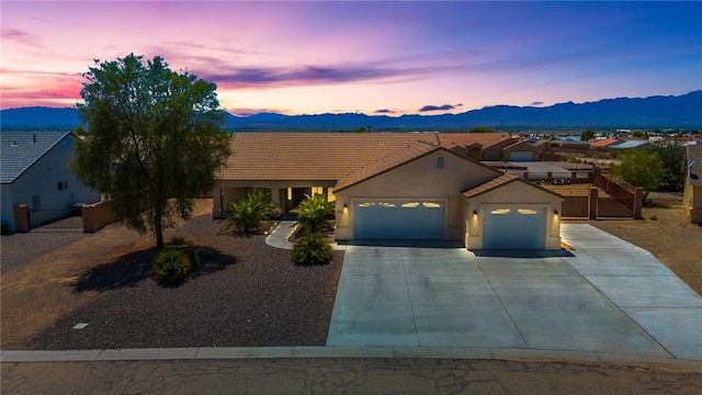6053 S Klamath Loop, Fort Mohave, AZ 86426 - view of front of house featuring a garage, concrete driveway, a mountain view, stucco siding, and a tiled roof
