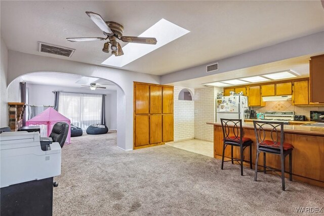 interior space with ceiling fan, brick wall, visible vents, and light colored carpet