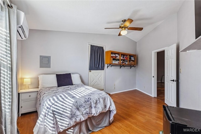 bedroom featuring a ceiling fan, vaulted ceiling, wood finished floors, a wall mounted air conditioner, and baseboards