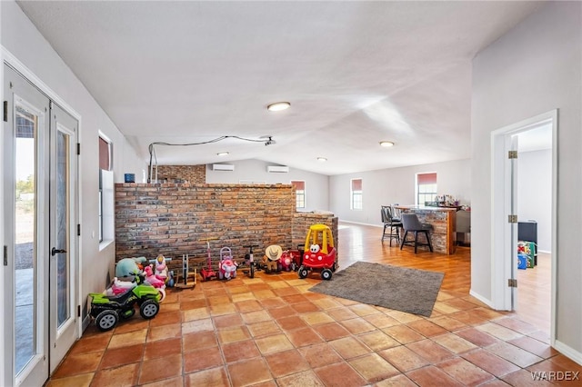 rec room with lofted ceiling, brick wall, baseboards, french doors, and a wall mounted AC