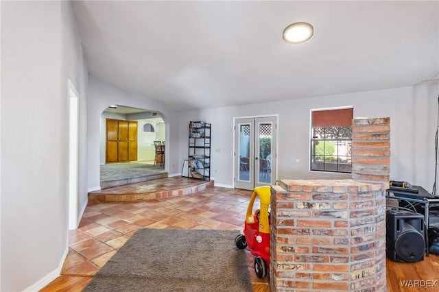 entryway with arched walkways, lofted ceiling, tile patterned flooring, baseboards, and french doors