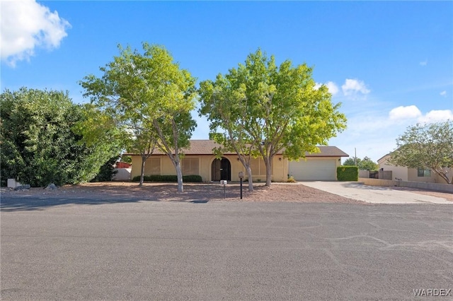 ranch-style house featuring a garage, fence, and concrete driveway