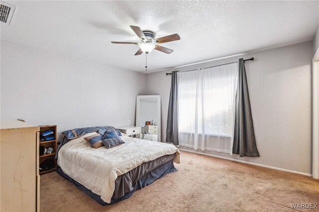 bedroom with baseboards, visible vents, a ceiling fan, light colored carpet, and a textured ceiling