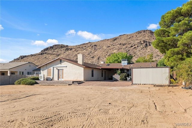 rear view of house with fence, a mountain view, and stucco siding