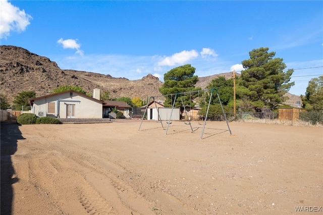 view of yard featuring playground community, fence, and a mountain view