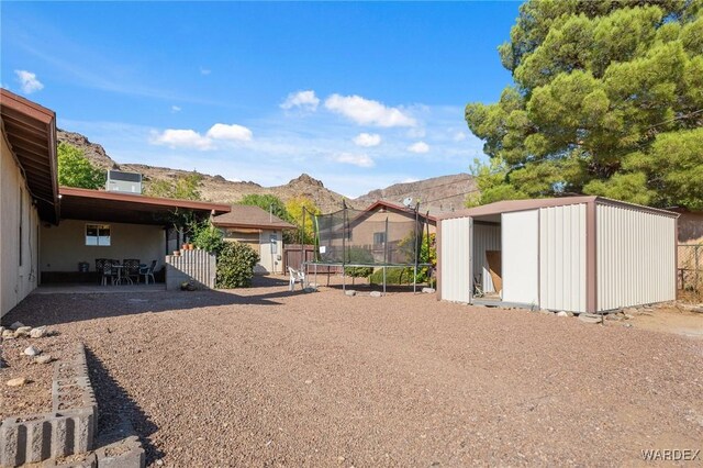 view of yard featuring a patio, a trampoline, central air condition unit, a shed, and a mountain view