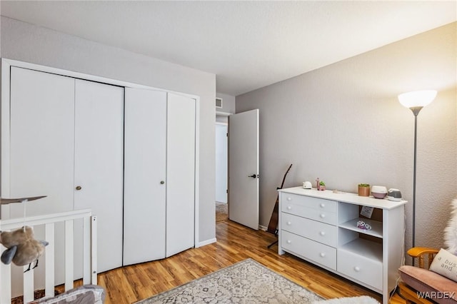 bedroom featuring light wood finished floors, visible vents, and a closet