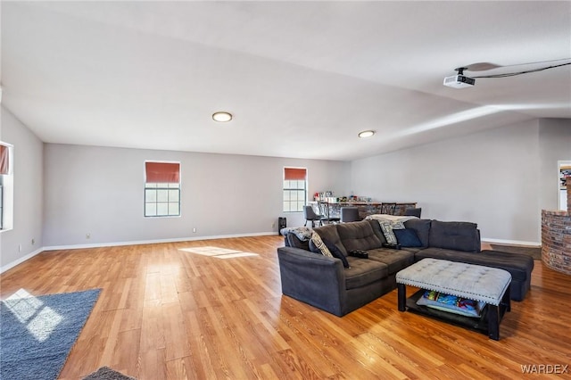 living area featuring lofted ceiling, light wood-style flooring, and baseboards