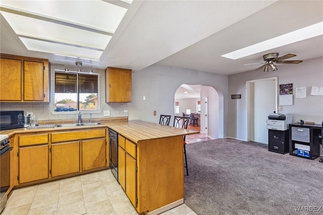 kitchen featuring light countertops, a sink, a peninsula, and black appliances