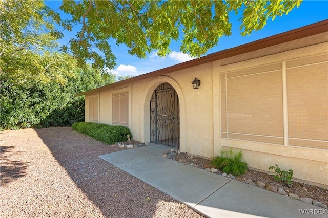 doorway to property with a gate and stucco siding