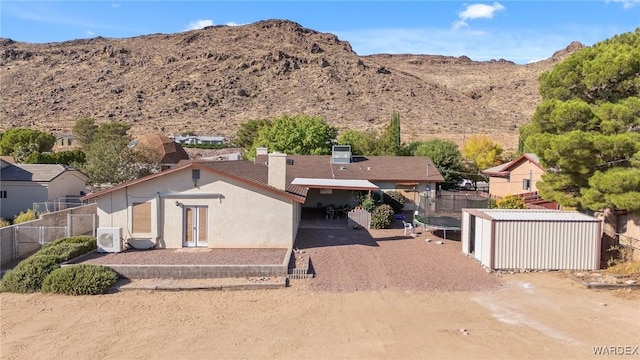 back of house featuring ac unit, fence, a mountain view, and stucco siding