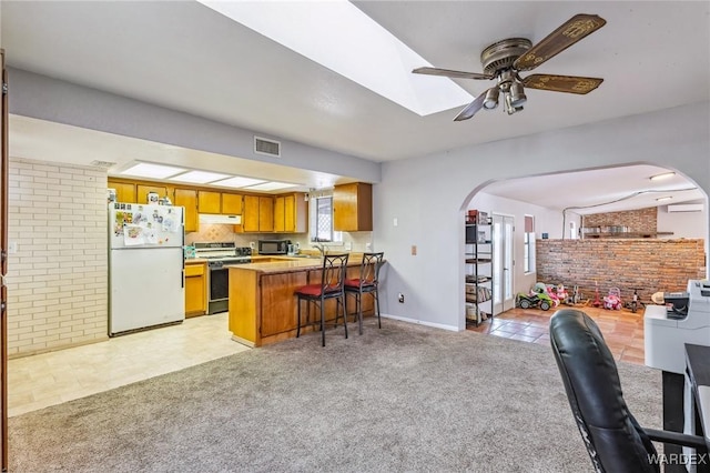 kitchen featuring light carpet, visible vents, freestanding refrigerator, a peninsula, and stainless steel stove