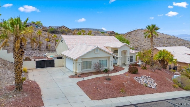 view of front of house featuring concrete driveway, a tile roof, fence, a mountain view, and stucco siding