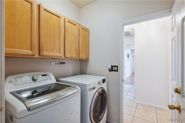 washroom featuring visible vents, light tile patterned flooring, washing machine and clothes dryer, and cabinet space