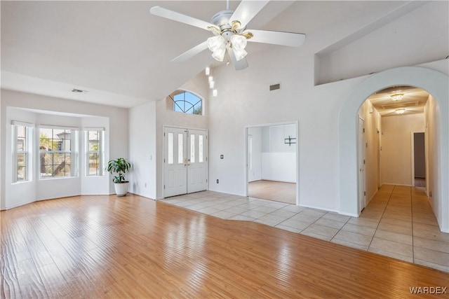 interior space with arched walkways, ceiling fan, light wood-type flooring, and visible vents