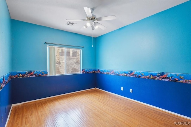 spare room with visible vents, ceiling fan, baseboards, and wood finished floors