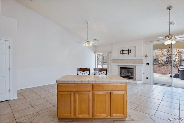 kitchen with tile counters, open floor plan, visible vents, and a ceiling fan