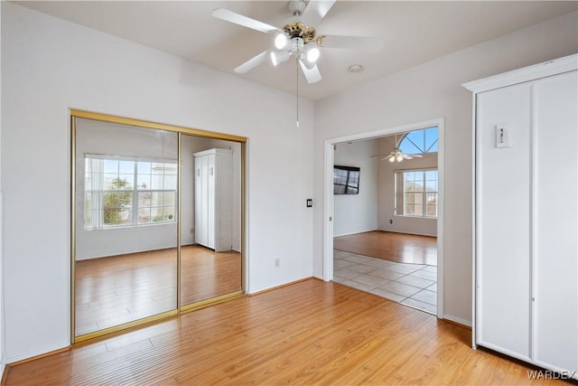 unfurnished bedroom featuring a ceiling fan, light wood-type flooring, and a closet