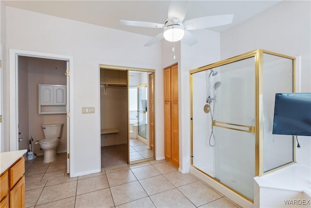 full bathroom featuring toilet, a ceiling fan, vanity, tile patterned floors, and a stall shower