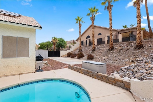 back of property featuring fence, a tiled roof, a swimming pool, and stucco siding