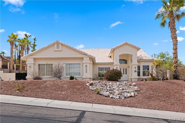 mediterranean / spanish home with a tile roof, fence, and stucco siding